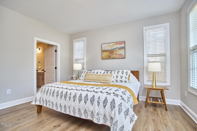 bedroom with baseboards, wood finished floors, and ensuite bathroom
