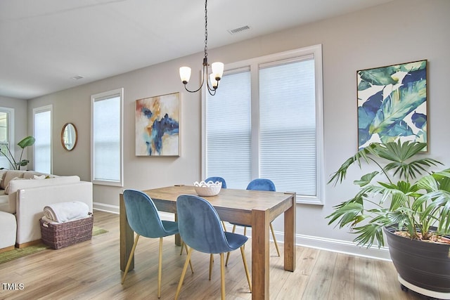 dining space with visible vents, baseboards, a chandelier, and light wood-type flooring