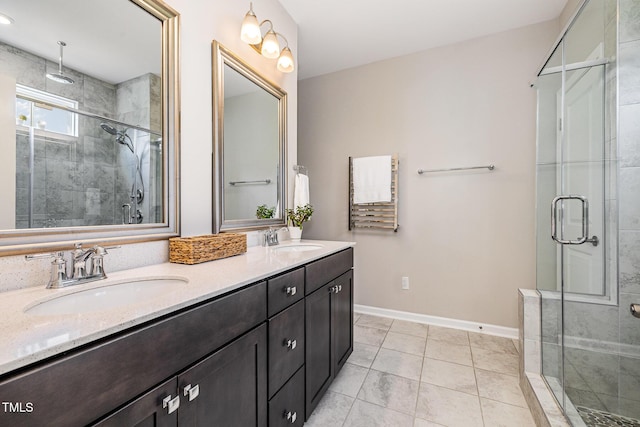 bathroom featuring a stall shower, baseboards, double vanity, and tile patterned floors