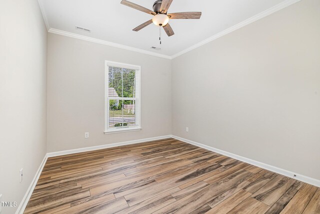 spare room featuring wood finished floors, crown molding, baseboards, and a ceiling fan