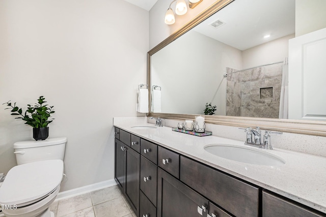 bathroom with toilet, baseboards, double vanity, and a tile shower