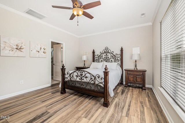 bedroom with light wood-style floors, crown molding, baseboards, and a ceiling fan