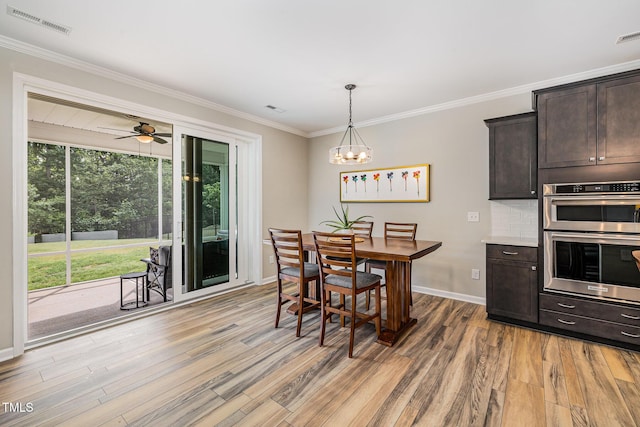 dining area featuring light wood-type flooring, crown molding, baseboards, a chandelier, and ceiling fan