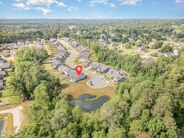 aerial view of property and surrounding area featuring nearby suburban area, a large body of water, and a heavily wooded area