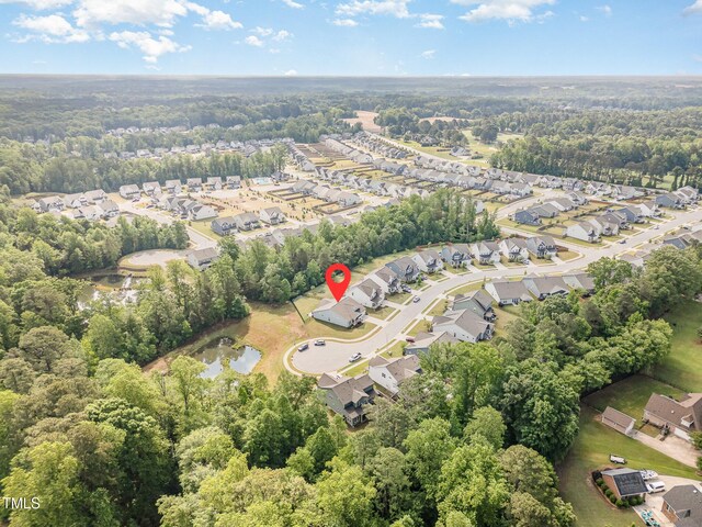 aerial view of property and surrounding area featuring nearby suburban area and a heavily wooded area