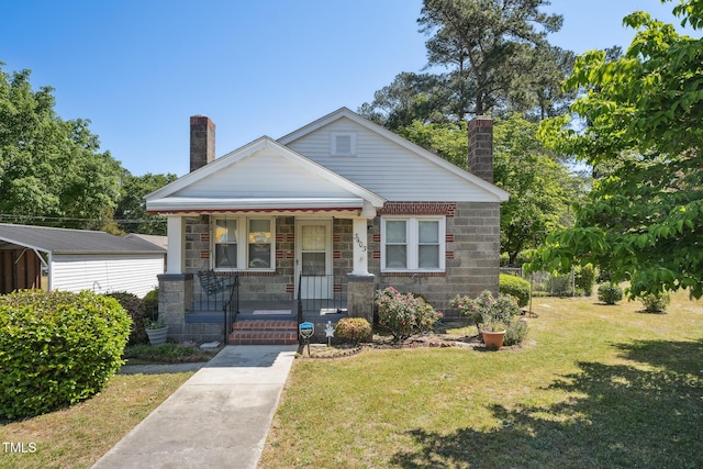 bungalow-style home with a porch, a front lawn, and a chimney