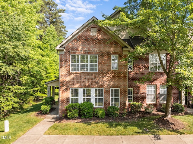 colonial home with a front yard and brick siding