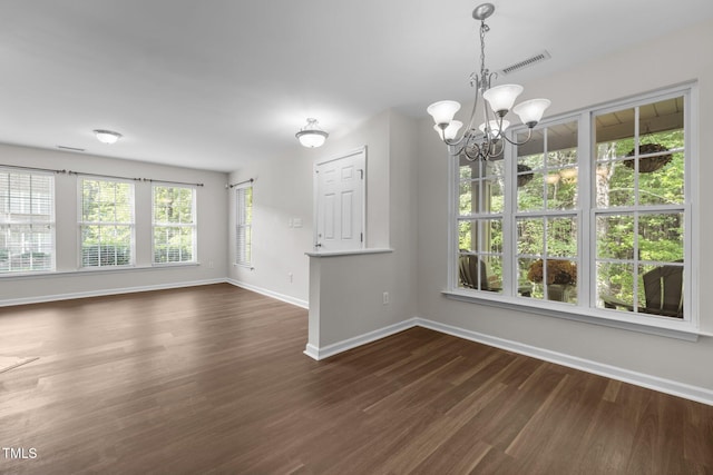 unfurnished dining area featuring baseboards, visible vents, a chandelier, and dark wood-style floors