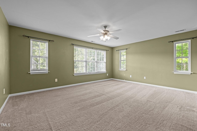 carpeted spare room with baseboards, a ceiling fan, and visible vents