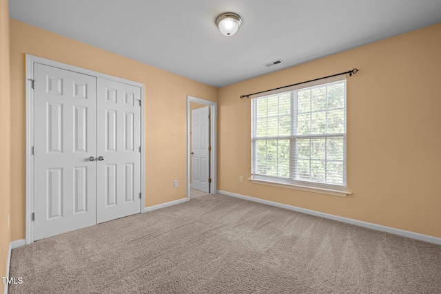 unfurnished bedroom featuring carpet floors, baseboards, visible vents, and a closet