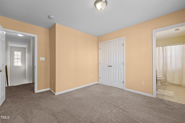 unfurnished bedroom with carpet floors, baseboards, and a closet