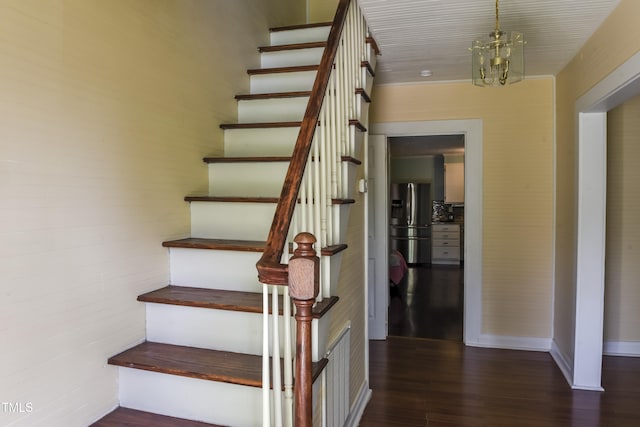 stairs with wood finished floors and a chandelier