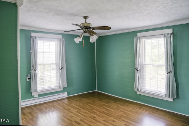 unfurnished room featuring a baseboard heating unit, ornamental molding, a textured ceiling, healthy amount of natural light, and wood finished floors