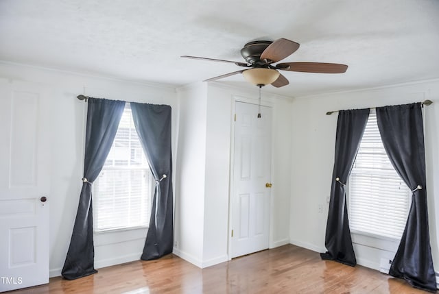 unfurnished bedroom with wood finished floors, ornamental molding, baseboards, and a ceiling fan
