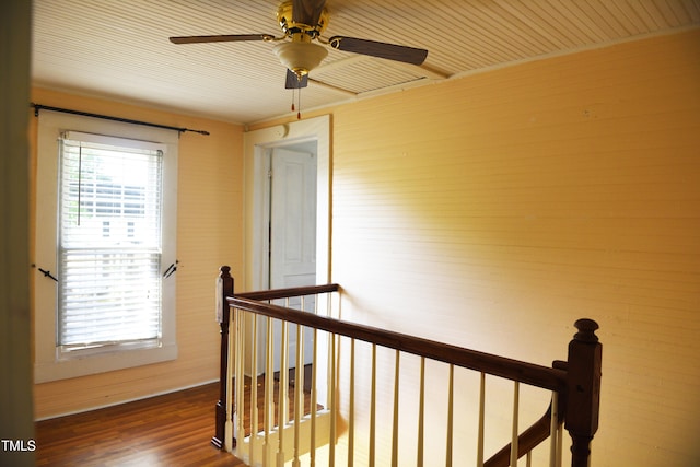 hall with an upstairs landing, healthy amount of natural light, and wood finished floors