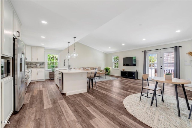 kitchen with a kitchen breakfast bar, an island with sink, open floor plan, wood finished floors, and ornamental molding