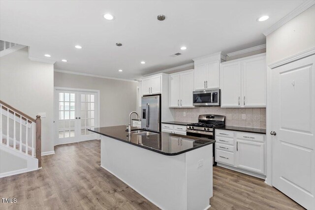 52 Brunello Ct, Clayton, NC 27527 - kitchen featuring crown molding, dark countertops, an island with sink, a sink, and appliances with stainless steel finishes