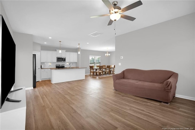 living room with ceiling fan with notable chandelier, recessed lighting, baseboards, light wood-type flooring, and visible vents
