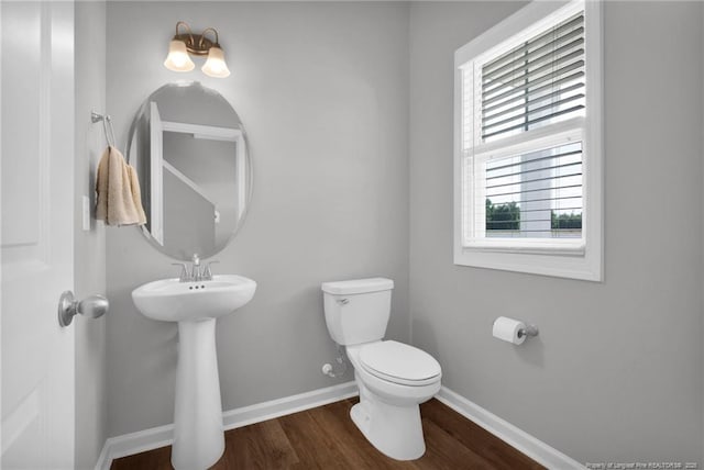 bathroom featuring baseboards, a sink, wood finished floors, and toilet