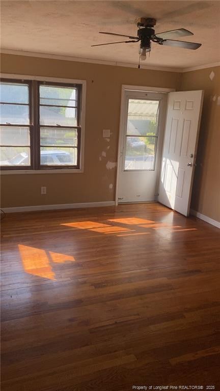 empty room with ornamental molding, a healthy amount of sunlight, and wood finished floors