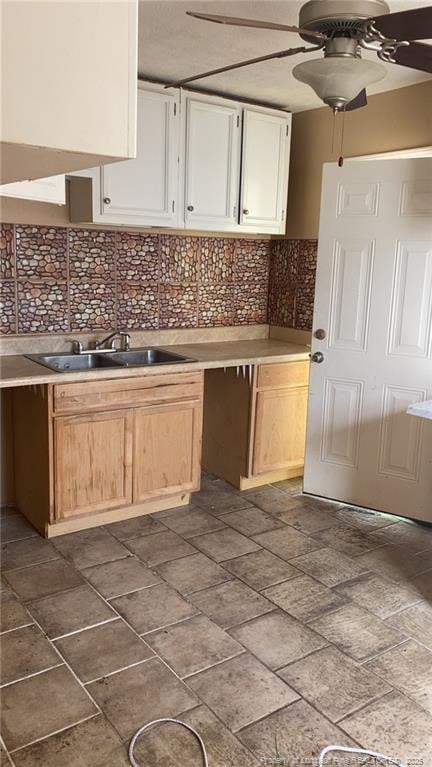 kitchen with a sink, white cabinetry, a ceiling fan, and decorative backsplash