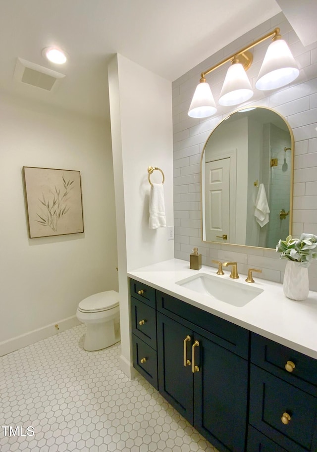 full bathroom featuring visible vents, a tile shower, vanity, baseboards, and toilet
