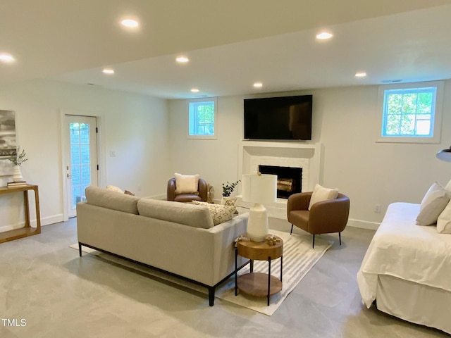 living room with a fireplace with raised hearth, baseboards, and recessed lighting