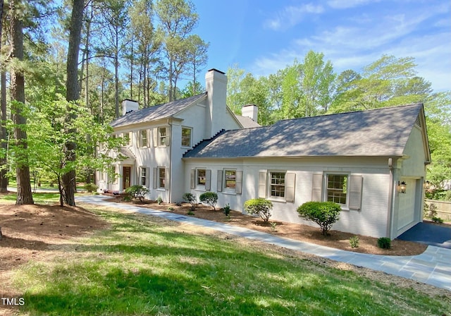 neoclassical home with a garage, driveway, and a chimney