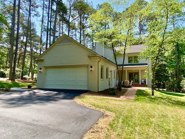 view of front of home featuring a chimney, a front yard, a garage, aphalt driveway, and stucco siding