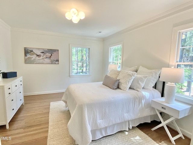 bedroom featuring multiple windows, baseboards, ornamental molding, and light wood finished floors