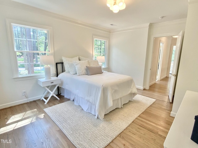 bedroom featuring baseboards, ornamental molding, and light wood finished floors