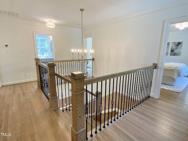 stairs with visible vents, crown molding, wood finished floors, baseboards, and a chandelier