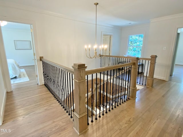 stairway with baseboards, an inviting chandelier, ornamental molding, and wood finished floors