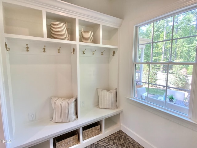 mudroom featuring dark tile patterned floors, baseboards, and a wealth of natural light