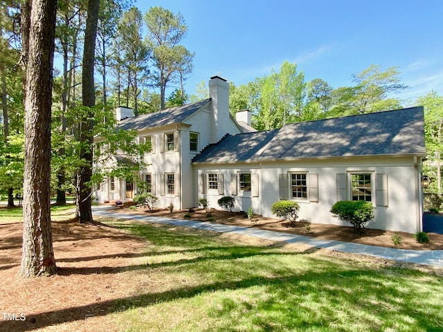 back of property featuring a lawn, roof with shingles, and a chimney