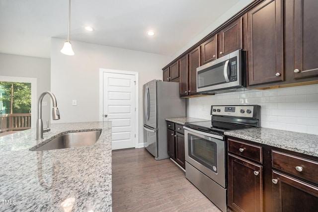 107 Cottage Ct, Youngsville, NC 27596 - kitchen with stainless steel appliances, backsplash, dark brown cabinetry, light stone countertops, and dark wood finished floors