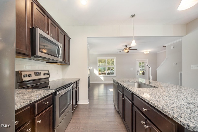 107 Cottage Ct, Youngsville, NC 27596 - kitchen featuring appliances with stainless steel finishes, dark wood-type flooring, backsplash, dark brown cabinets, and light stone countertops