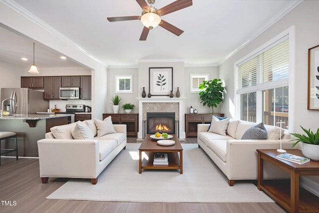 107 Cottage Ct, Youngsville, NC 27596 - living room featuring light wood-type flooring, ceiling fan, crown molding, a glass covered fireplace, and recessed lighting