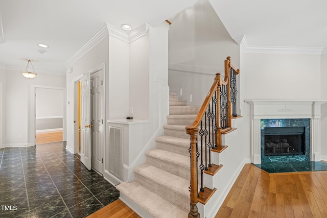 staircase featuring visible vents, baseboards, ornamental molding, recessed lighting, and a premium fireplace