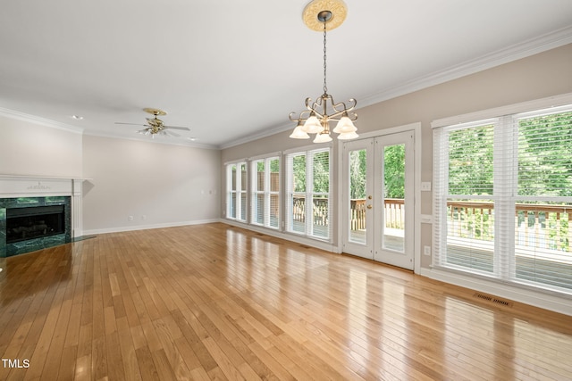 unfurnished living room with visible vents, crown molding, a fireplace, light wood-style flooring, and ceiling fan with notable chandelier