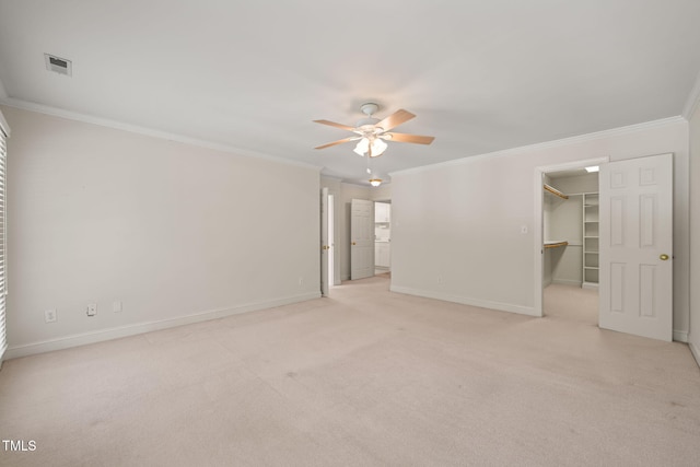 unfurnished bedroom with light carpet, a walk in closet, baseboards, visible vents, and ornamental molding
