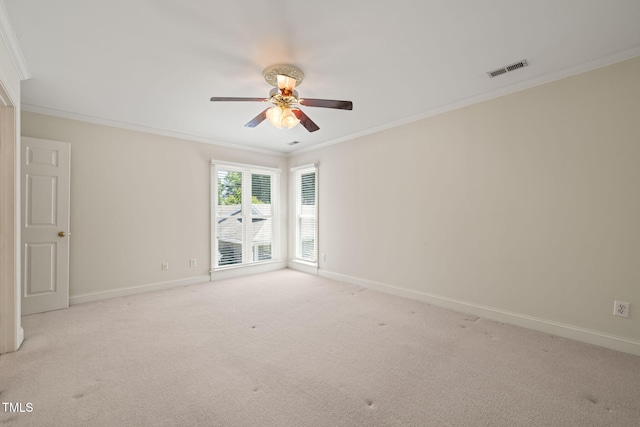 spare room featuring light colored carpet, a ceiling fan, baseboards, visible vents, and ornamental molding