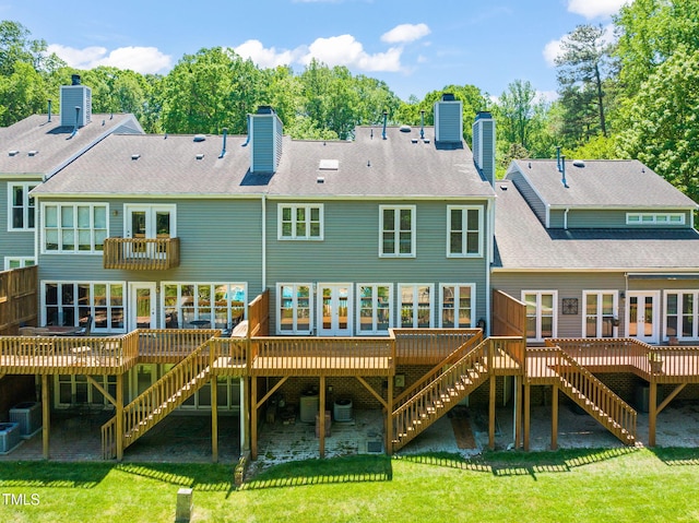 rear view of house with a lawn, a chimney, stairway, and a deck