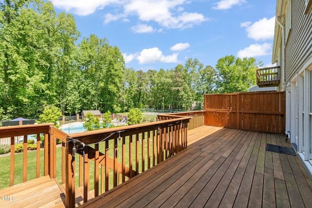 wooden terrace with a lawn, a fenced backyard, and a pool