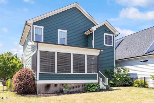 rear view of house featuring fence, a lawn, and a sunroom