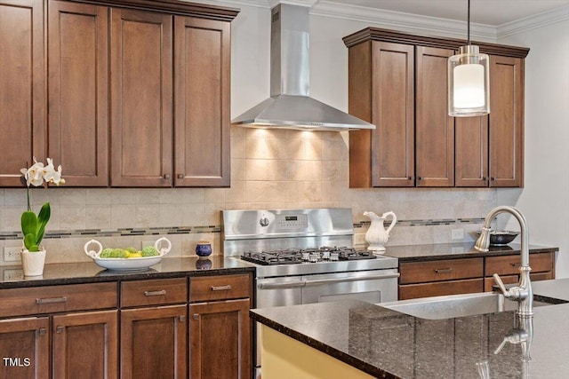 kitchen featuring wall chimney range hood, gas stove, a sink, decorative backsplash, and pendant lighting