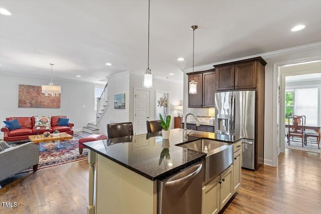 kitchen featuring a sink, appliances with stainless steel finishes, ornamental molding, and wood finished floors