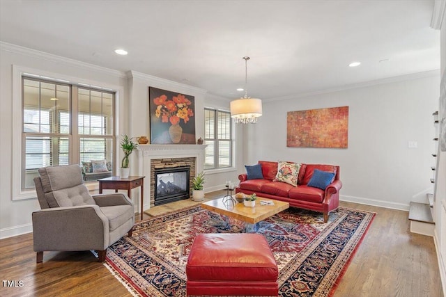 living room with ornamental molding, wood finished floors, baseboards, a stone fireplace, and recessed lighting