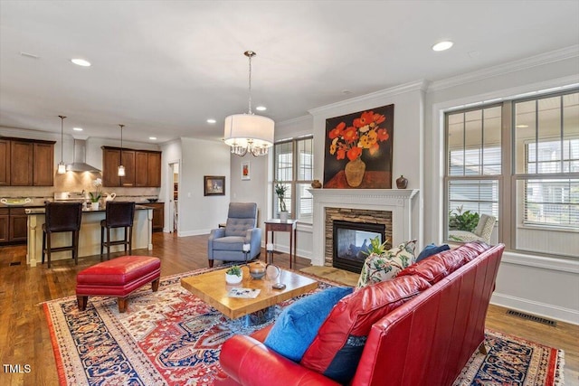 living area with dark wood-style flooring, recessed lighting, visible vents, and ornamental molding