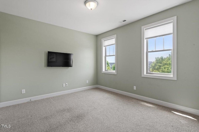 unfurnished room featuring baseboards, visible vents, and carpet